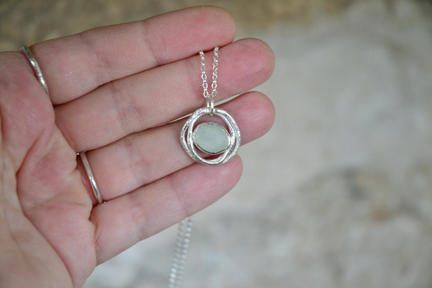 Pale blue seafoam sea glass, set in silver and held between two molten silver rings.