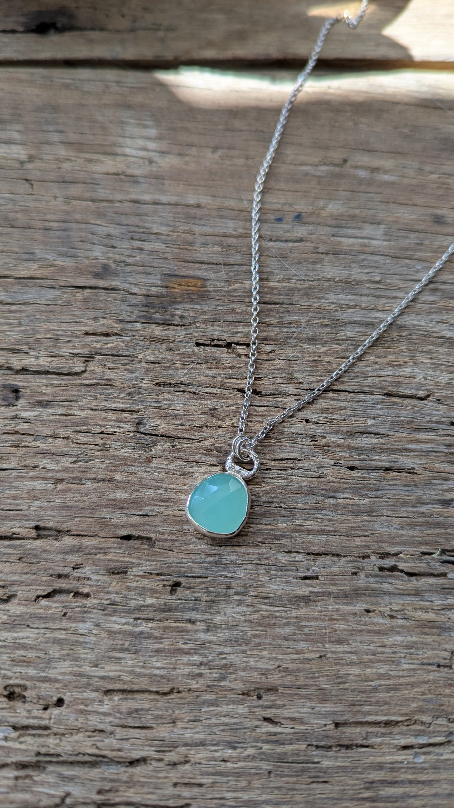 Necklace with a turquoise coloured pendant on a wooden surface