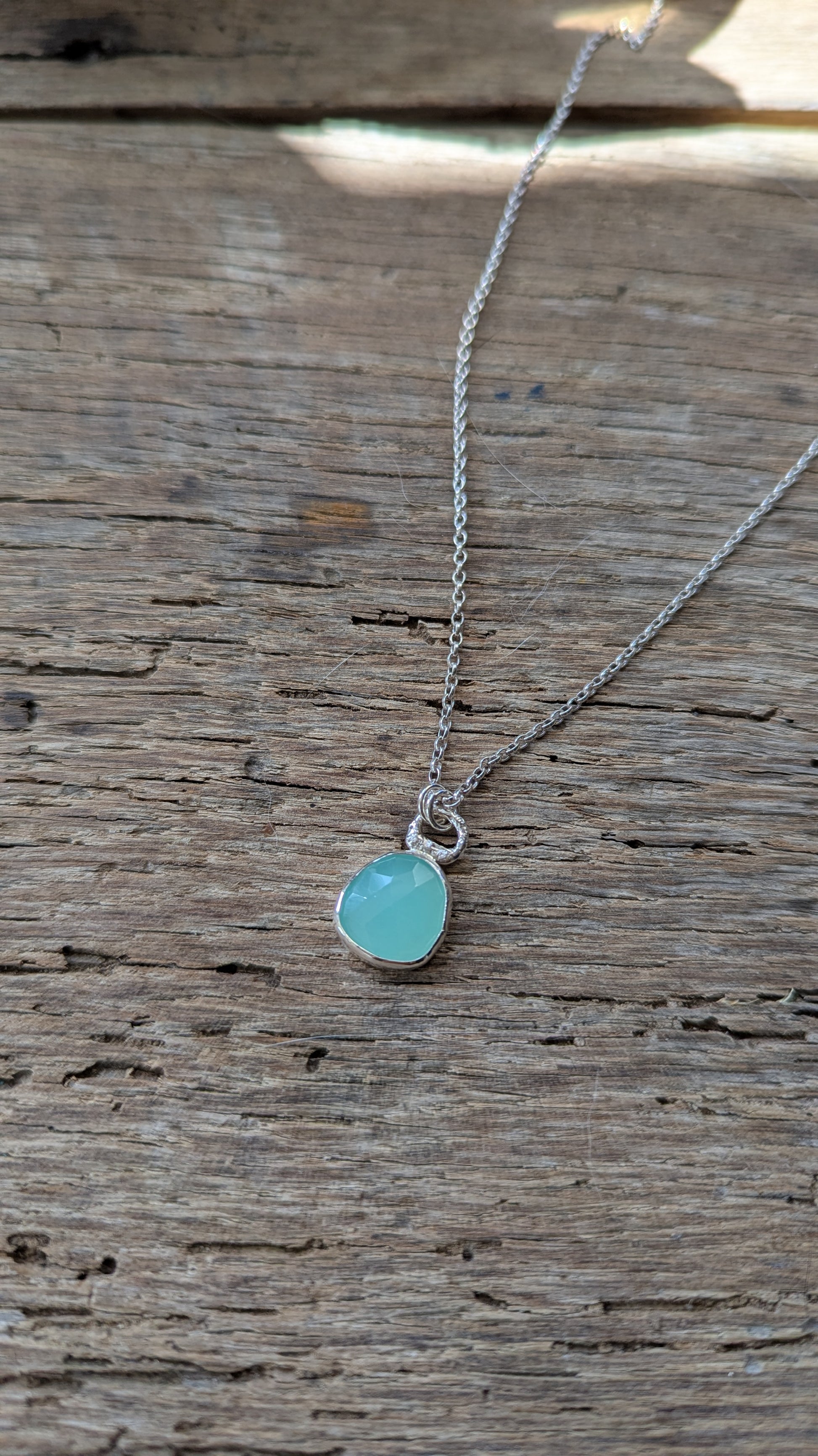 Necklace with a turquoise coloured pendant on a wooden surface