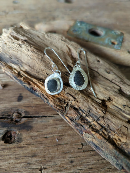 black sea glass earrings on driftwood