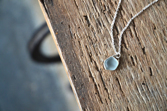 Necklace with a teardrop-shaped pendant on a wooden surface